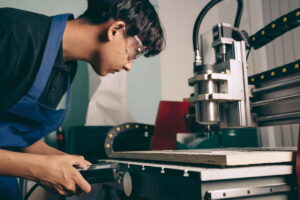Un aprendiz con gafas de seguridad maneja una máquina CNC en su centro de formación.
