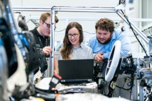 Unos ingenieros discuten problemas de un proyecto automovilístico utilizando tecnología moderna. El factor decisivo será probablemente la creciente escasez de trabajadores cualificados en Alemania. La evolución demográfica juega aquí un papel fundamental.