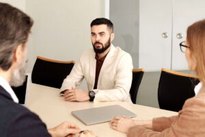 Dos responsables de recursos humanos entrevistan a un candidato a un puesto de trabajo en una gran mesa de reuniones, dentro de una sala de conferencias moderna. El método STAR ayuda a presentar experiencias profesionales con ejemplos concretos y demostrar competencias durante una entrevista laboral en Alemania.