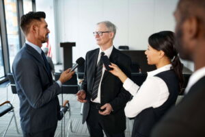 Journalisten mitten in einem Interview mit einem leitenden Angestellten in einem Konferenzraum. El sector periodístico en Alemania afronta recortes masivos y el auge de la IA, exigiendo más verificación e investigación propia.