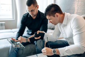 Dos hombres comentan gráficos digitales en una sala de reuniones. Las empresas con cogestión lideran la transformación digital en Alemania, pero un plan legal de la Unión Europea amenaza este modelo paritario.