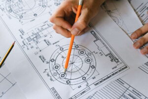 Un especialista revisa planos técnicos en su escritorio y sostiene un lápiz en la mano. La nueva norma ISO 9001 refuerza el liderazgo directivo, la ética y la gestión estratégica en las organizaciones sin alterar su estructura base.