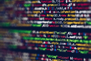 En primer plano, ovejas; al fondo, código de programación desenfocado en una pantalla, simbolizando la programación de inteligencia artificial. El 27% de la Generación Z en Alemania depende de la IA para trabajar, mientras el país registra un 19% de adopción general frente al contexto europeo.