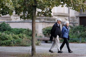 Una pareja de ancianos pasa junto a un árbol en un parque urbano, en un día temprano y frío. Casi la mitad en Alemania anhela un retiro a los 60, pero la incertidumbre económica y la presión financiera frenan su verdadera libertad.
